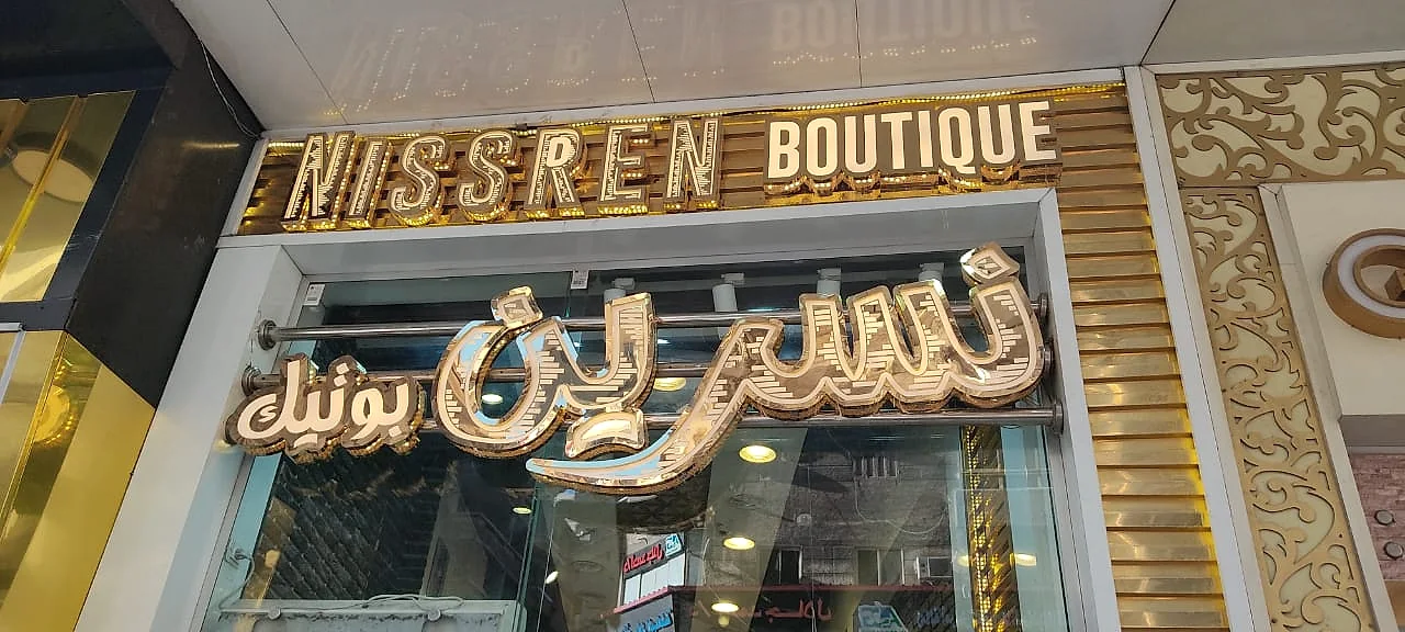 NISSREEN BOUTIQUE — حروف ديكورية ذهبية مجسمة بإضاءة داخلية على واجهة زجاجية وكسوة بخطوط ذهبية. من تنفيذ أبو الخير